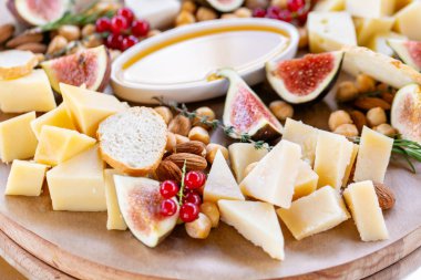 Peynir tabağı. Lezzetli peynir karışımı baget kruton, frenk üzümü, tatlı incir, badem, bal ahşap masa üzerinde. Ahşap bir tabakta yemek tatma. Yiyecek şarap için. Keçi peyniri, Parmesan, Gouda