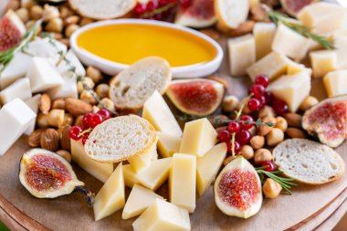 Işık İtalyan aperatifleri. Akşam yemeği açık büfe masada. Peynir tabağı. Lezzetli peynir karışımı ahşap masa üzerinde. Ahşap bir tabakta yemek tatma. Yiyecek şarap.