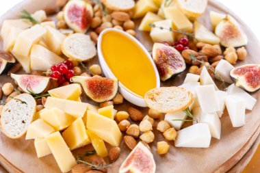 Peynir tabağı. Lezzetli peynir karışımı baget kruton, frenk üzümü, tatlı incir, badem, bal ahşap masa üzerinde. Ahşap bir tabakta yemek tatma. Yiyecek şarap için. Keçi peyniri, Parmesan, Gouda