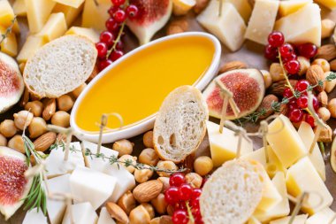 Peynir tabağı. Lezzetli peynir karışımı baget kruton, frenk üzümü, tatlı incir, badem, bal ahşap masa üzerinde. Ahşap bir tabakta yemek tatma. Yiyecek şarap için. Keçi peyniri, Parmesan, Gouda