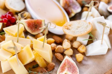 Işık İtalyan aperatifleri. Akşam yemeği açık büfe masada. Peynir tabağı. Lezzetli peynir karışımı ahşap masa üzerinde. Ahşap bir tabakta yemek tatma. Yiyecek şarap.