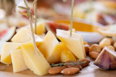 Işık İtalyan aperatifleri. Akşam yemeği açık büfe masada. Peynir tabağı. Lezzetli peynir karışımı ahşap masa üzerinde. Ahşap bir tabakta yemek tatma. Yiyecek şarap.