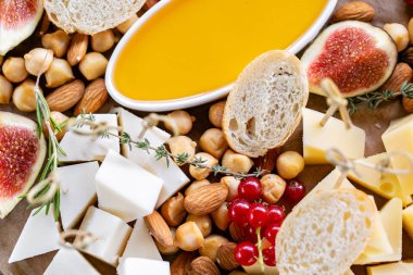 Peynir tabağı. Lezzetli peynir karışımı baget kruton, frenk üzümü, tatlı incir, badem, bal ahşap masa üzerinde. Ahşap bir tabakta yemek tatma. Yiyecek şarap için. Keçi peyniri, Parmesan, Gouda