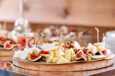 Peynir tabağı. Lezzetli peynir karışımı baget kruton, frenk üzümü, tatlı incir, badem, bal ahşap masa üzerinde. Ahşap bir tabakta yemek tatma. Yiyecek şarap için. Keçi peyniri, Parmesan, Gouda