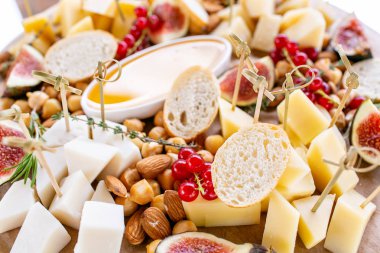 Peynir tabağı. Lezzetli peynir karışımı baget kruton, frenk üzümü, tatlı incir, badem, bal ahşap masa üzerinde. Ahşap bir tabakta yemek tatma. Yiyecek şarap için. Keçi peyniri, Parmesan, Gouda