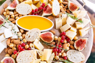 Peynir tabağı. Lezzetli peynir karışımı baget kruton, frenk üzümü, tatlı incir, badem, bal ahşap masa üzerinde. Ahşap bir tabakta yemek tatma. Yiyecek şarap için. Keçi peyniri, Parmesan, Gouda