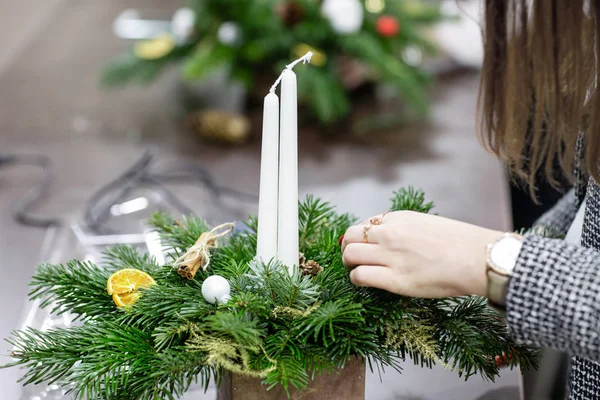 Een vrouw versiert een Kerststuk met kaarsen. Close-up van de handen. Masterclass op het maken van decoratieve ornamenten. Kerst decor met hun eigen handen. De nieuwe jaarviering. Bloemenwinkel — Stockfoto