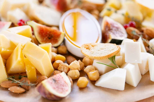 Light Italian snacks. A buffet table at a dinner party. Cheese plate. Delicious cheese mix on wooden table. Tasting dish on a wooden plate. Food for wine. — Stock Photo, Image