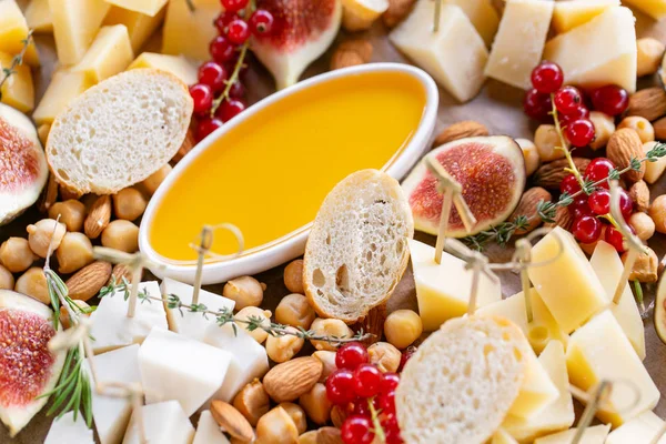 Peynir tabağı. Lezzetli peynir karışımı baget kruton, frenk üzümü, tatlı incir, badem, bal ahşap masa üzerinde. Ahşap bir tabakta yemek tatma. Yiyecek şarap için. Keçi peyniri, Parmesan, Gouda