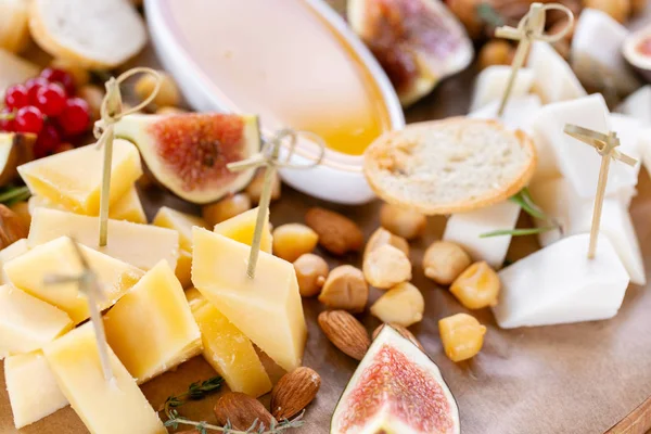 Işık İtalyan aperatifleri. Akşam yemeği açık büfe masada. Peynir tabağı. Lezzetli peynir karışımı ahşap masa üzerinde. Ahşap bir tabakta yemek tatma. Yiyecek şarap.