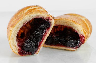 Lezzetli puf böreği tatlısı yarıya. Meyve ile lezzetli hamur işleri üzerinde açık renkli reçel. siyah kuş üzümü ya da yaban mersini