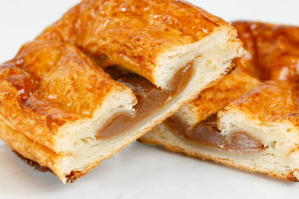 Lezzetli puf böreği tatlısı yarıya. Meyve ile lezzetli hamur işleri üzerinde açık renkli reçel. yoğunlaştırılmış süt