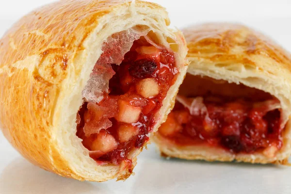 Lezzetli puf böreği tatlısı yarıya. Meyve ile lezzetli hamur işleri üzerinde açık renkli reçel. Berry, elma, armut