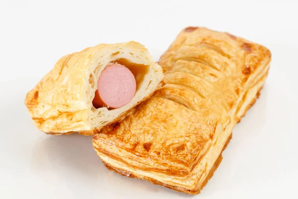 Tasty puff pastry dessert cut in half . Delicious pastries with sausage on light background. hot dog — Stock Photo, Image