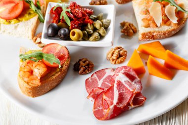 İtalyan meze plakalı. Bir kiraz domates Bruschetta ve karides. Parmesan peyniri, salam, yeşil kapari, zeytin, kurutulmuş domates ve ceviz.