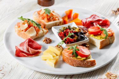İtalyan meze plakalı. Bir kiraz domates Bruschetta ve karides. Parmesan peyniri, salam, yeşil kapari, zeytin, kurutulmuş domates ve ceviz.