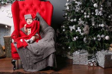 Küçük çocuk bir şapka ve atkı, kırmızı bir sandalyede oturan bir kardan adam giyinmiş. Çocuk eğleniyor Noel ağacı yakınındaki oturma odasında. Sevgi dolu aile oğlu mutlu Noeller ve mutlu yeni yıl.