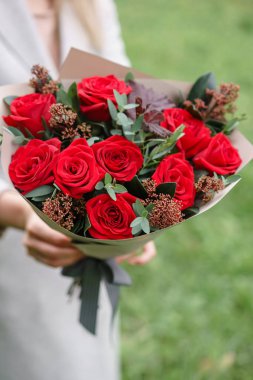 Güzel bir sonbahar buket tutan güzel kadın. karanfil ve kırmızı bahçe gül çiçek aranjmanı. Pembe renk. zemin üzerine yeşil çim