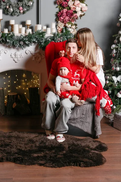 Sevgi dolu aile mutlu Noeller ve mutlu yeni yıl. Neşeli güzel insanlar. Anne, baba ve küçük bebek evlat. Anne ve çocuk Noel ağacı ve beyaz şömine yakın kapalı eğleniyor. — Stok fotoğraf