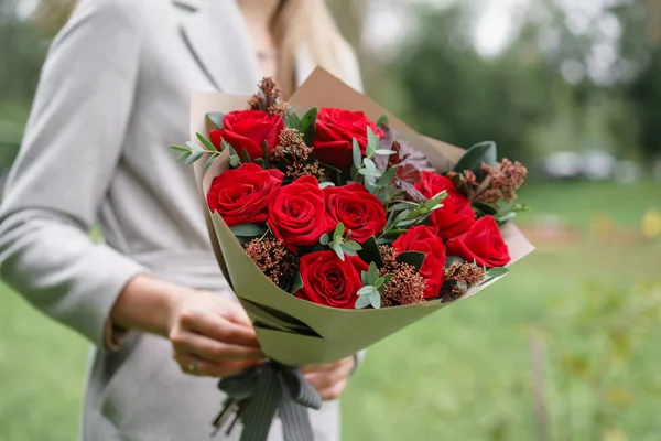 Mulher encantadora segurando um lindo buquê de outono. arranjo de flores com eucalipto e rosas vermelhas do jardim. Cor rosa. gramado verde no fundo — Fotografia de Stock