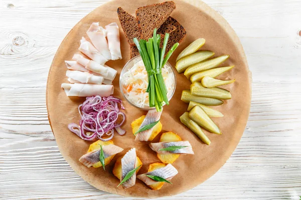 Sandwich on fried potatoes with herring, green onion. Tasty appetizer with sauerkraut, pickled cucumber, mustard on wooden Board. Rye bread and lard — Stock Image Sandwich on fried potatoes with herring, green onion. Tasty appetizer with sauerkraut, pickled cucumber, mustard on wooden Board. Rye bread and lard Stock Picture
