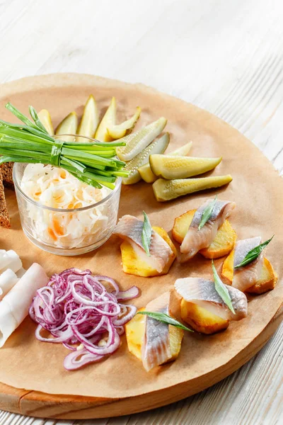Sandwich on fried potatoes with herring, green onion. Tasty appetizer with sauerkraut, pickled cucumber, mustard on wooden Board. Rye bread and lard — Stock Image Sandwich on fried potatoes with herring, green onion. Tasty appetizer with sauerkraut, pickled cucumber, mustard on wooden Board. Rye bread and lard Stock Picture