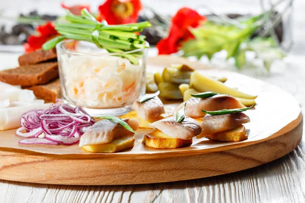 Sandwich on fried potatoes with herring, green onion. Tasty appetizer with sauerkraut, pickled cucumber, mustard on wooden Board. Rye bread and lard — Stock Image Sandwich on fried potatoes with herring, green onion. Tasty appetizer with sauerkraut, pickled cucumber, mustard on wooden Board. Rye bread and lard Royalty Free Stock Photos