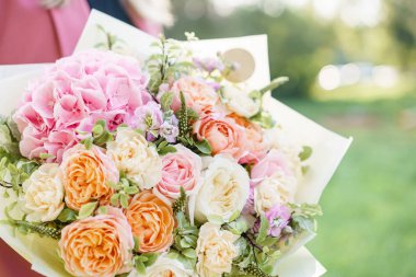 Bir güzel bahar buket tutan güzel kadın. Ortanca ve bahçe gül çiçek aranjmanı. Pembe renk. zemin üzerine yeşil çim