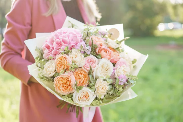 Прекрасна жінка тримає гарний весняний букет. квіткова композиція з гортензією і садовими трояндами. Колір рожевий. зелений газон на фоні — стокове фото