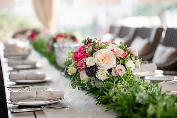 Neatly twisted into a tube dining room napkin decorated with a sprig of pistachio. Wedding Banquet or gala dinner. The chairs and table for guests, served with cutlery and crockery. party on terrace