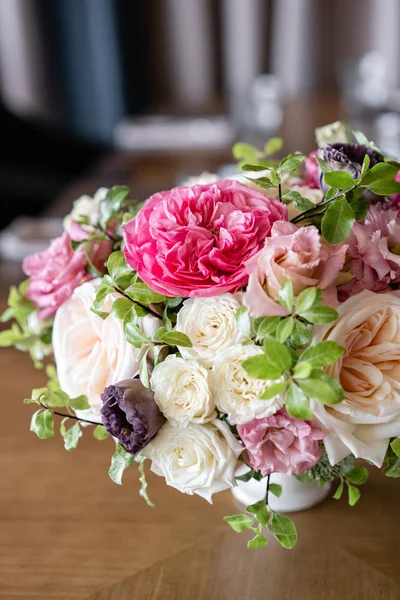 在柔和的颜色和明亮的口音安排鲜花。婚礼背景。餐桌上的餐厅。木桌上一盏灯花瓶里的花园和灌木玫瑰的不同品种 — 图库照片