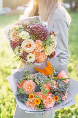 iki güzel bahar buket. Bir çiçek düzenlemeleri ile renklerin çeşitli tutan genç kız. Mor, mavi ve şeftali renkli çiçek. Parlak şafak veya günbatımı güneş