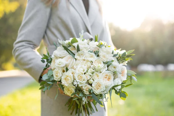 Young girl holding a beautiful spring bouquet. flower arrangement with white flowers. Bright dawn or sunset sun — Stock Photo, Image