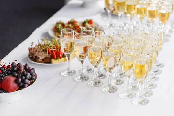 Barista versando champagne o vino in bicchieri di vino sul tavolo del ristorante. solenne cerimonia nuziale o felice anno nuovo banchetto — Foto Stock
