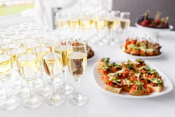 Solemn happy new year banquet. Lot of glasses champagne or wine on the table in restaurant. buffet table with lots of delicious snacks. canapes, bruschetta, and little desserts on wooden plate board — Stock Photo, Image