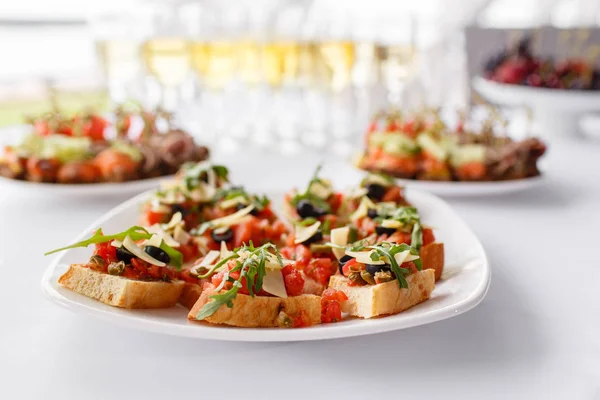 Teller mit italienischen Vorspeisen. Bruschetta mit Kirschtomaten und Garnelen. Parmesan, Oliven, sonnengetrocknete Tomaten und Walnüsse. — Stockfoto