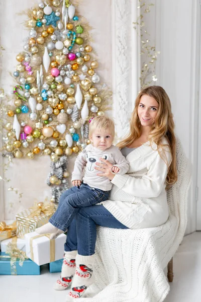 Šťastná rodina portrét v Home - mladá Těhotná maminka objímá svého malého syna. Šťastný nový rok. zdobené vánoční strom. Vánoční dopoledne v obývací pokoj. — Stock fotografie