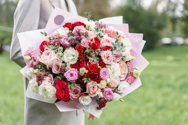 Lovely woman holding a beautiful autumn bouquet. flower arrangement with pink and red color flowers. green lawn on background. — Stock Photo, Image