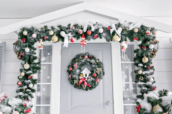 Πρωί Χριστουγέννων. είσοδο σπιτιού διακοσμημένα για διακοπές. Χριστουγεννιάτικη διακόσμηση. Γιρλάντα έλατο τα κλαδιά και τα φώτα στο κιγκλίδωμα — Φωτογραφία Αρχείου