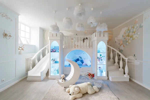 interior of a spacious childrens room. decorative castle with bed inside, game slide and stairs