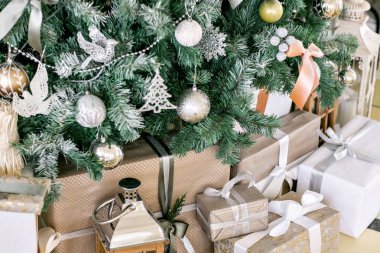 Noel Ağacı 'nın altında hediyeler ve hediye kutuları. Kurdeleli bej kutular. Yeni yıl dekore edilmiş ev içi. Kış Tatili konsepti.