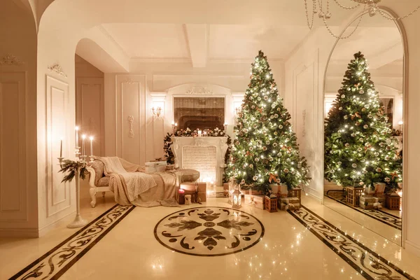 Classical interior of a white room. Christmas evening by candlelight. classic apartments with a white fireplace, decorated christmas tree, sofa, large windows and chandelier. — Stock Photo, Image