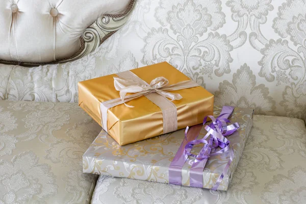 プレゼントとギフト用のソファの上の箱。リボンの弓で囲まれたボックス。新年装飾家のインテリア。冬休みのコンセプト. — ストック写真