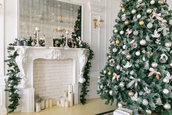 Árbol de Navidad decorado, en el primer plano bolas en las ramas y arcos. Apartamentos clásicos con chimenea. Noche de Navidad. Regalos en el árbol de Navidad . — Foto de Stock