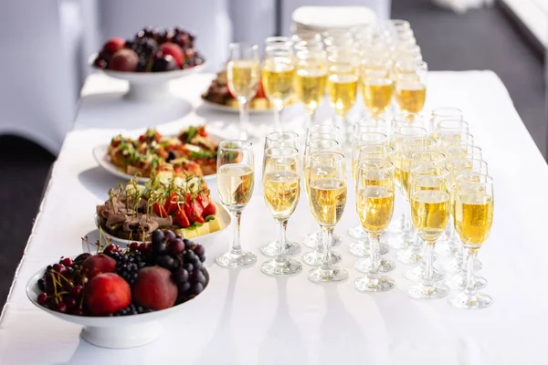 Solemn happy new year banquet. Lot of glasses champagne or wine on the table in restaurant. buffet table with lots of delicious snacks. canapes, bruschetta, and little desserts on wooden plate board — Stock Photo, Image