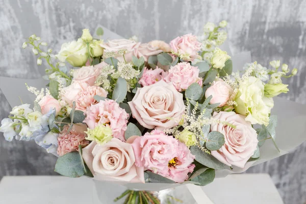Schöner Strauß gemischter Blumen in einer Vase auf einem Holztisch. die Arbeit des Blumenhändlers in einem Blumenladen. mattierte Plastikfolie — Stockfoto