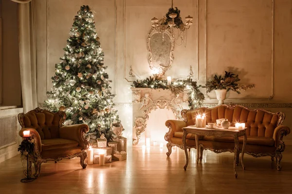 크리스마스 트리, garlands, 양 초, 손전등, 저녁에 선물. 클래식 인테리어 장식된 벽난로와 화이트 룸의 소파, — 스톡 사진