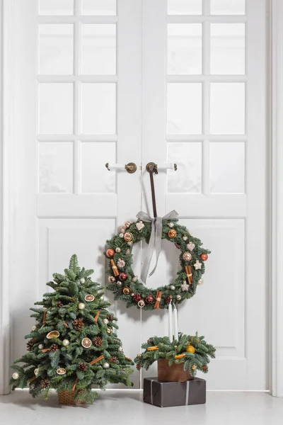 La decoración de la casa antes de las vacaciones de año nuevo. Conjunto de elementos decorativos con guirnalda de ramas de abeto, árbol de Navidad y arreglo en una caja de madera —  Fotos de Stock