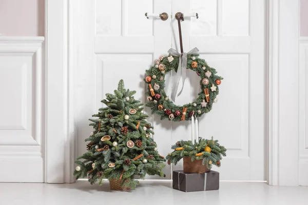Decoration of the house before the new year holidays. Set of decorative elements with fir branches wreath, Christmas tree and arrangement in a wooden box