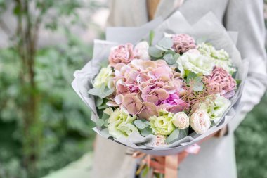 Genç kız güzel bahar buket tutarak. Ortanca ve bahçe gül çiçek aranjmanı. Parlak şafak veya günbatımı güneş